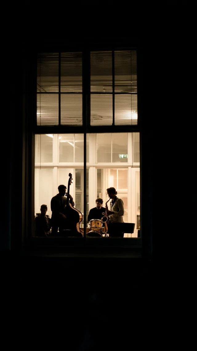through the window at night in a new york loft are jazz musicians playing jazz, they are further in the room,